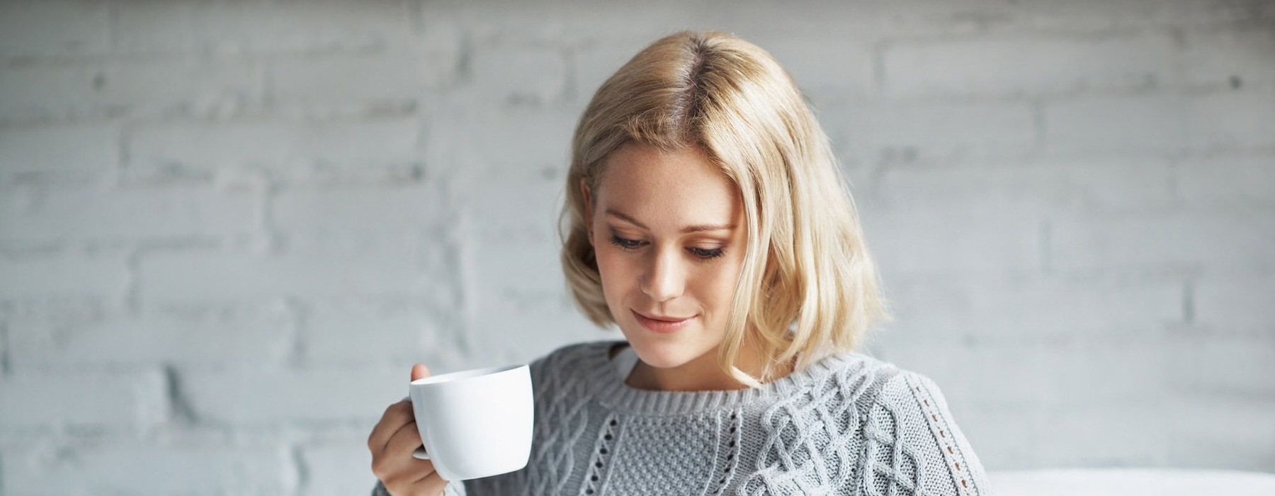 a person sitting down holding a cup looking at a tablet