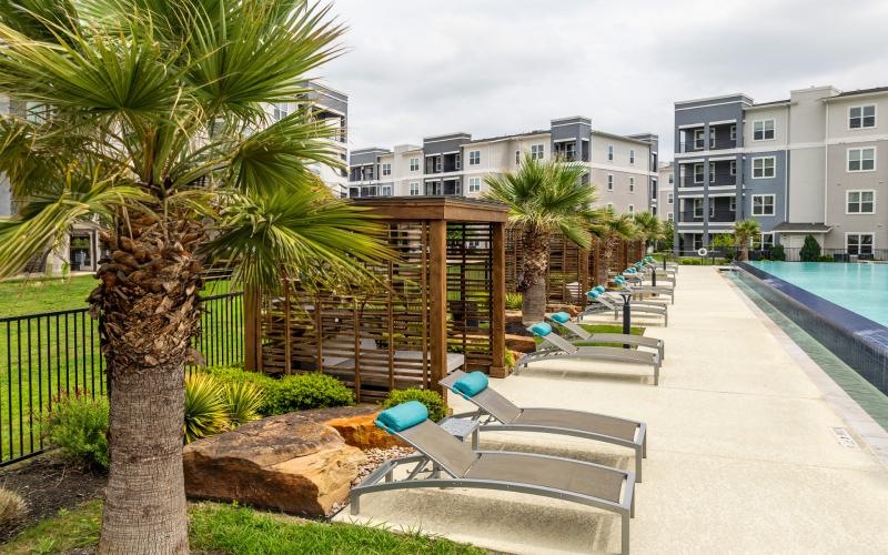 a pool and lounge chairs by a building
