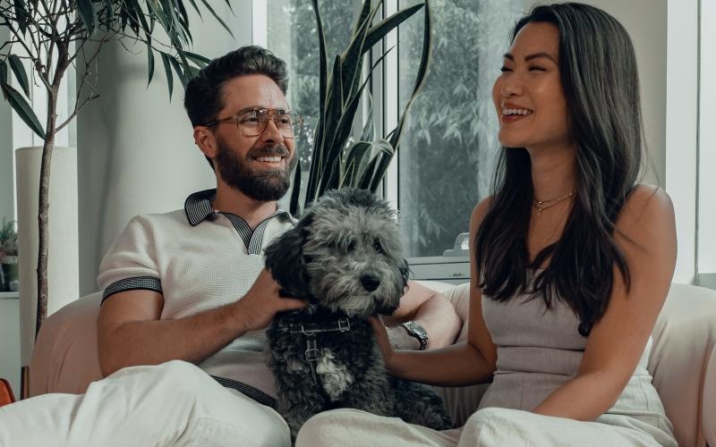 a man and woman sitting on a couch with a dog